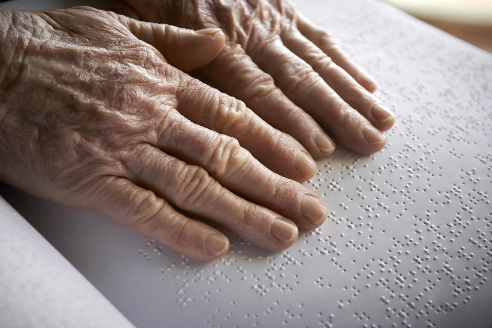 Old womans hands, reading a book with braille language