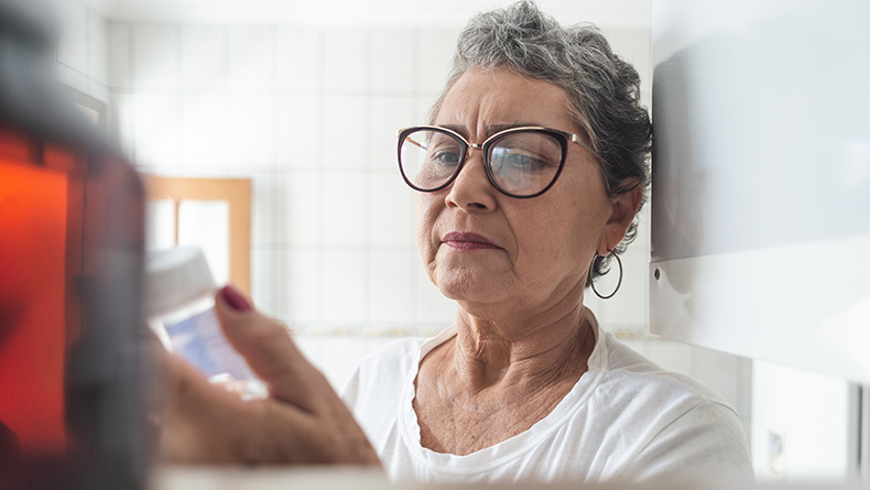 Woman looks at bottle of medication.