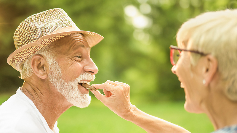 A happy woman putting a piece of chocolate in a man’s mouth