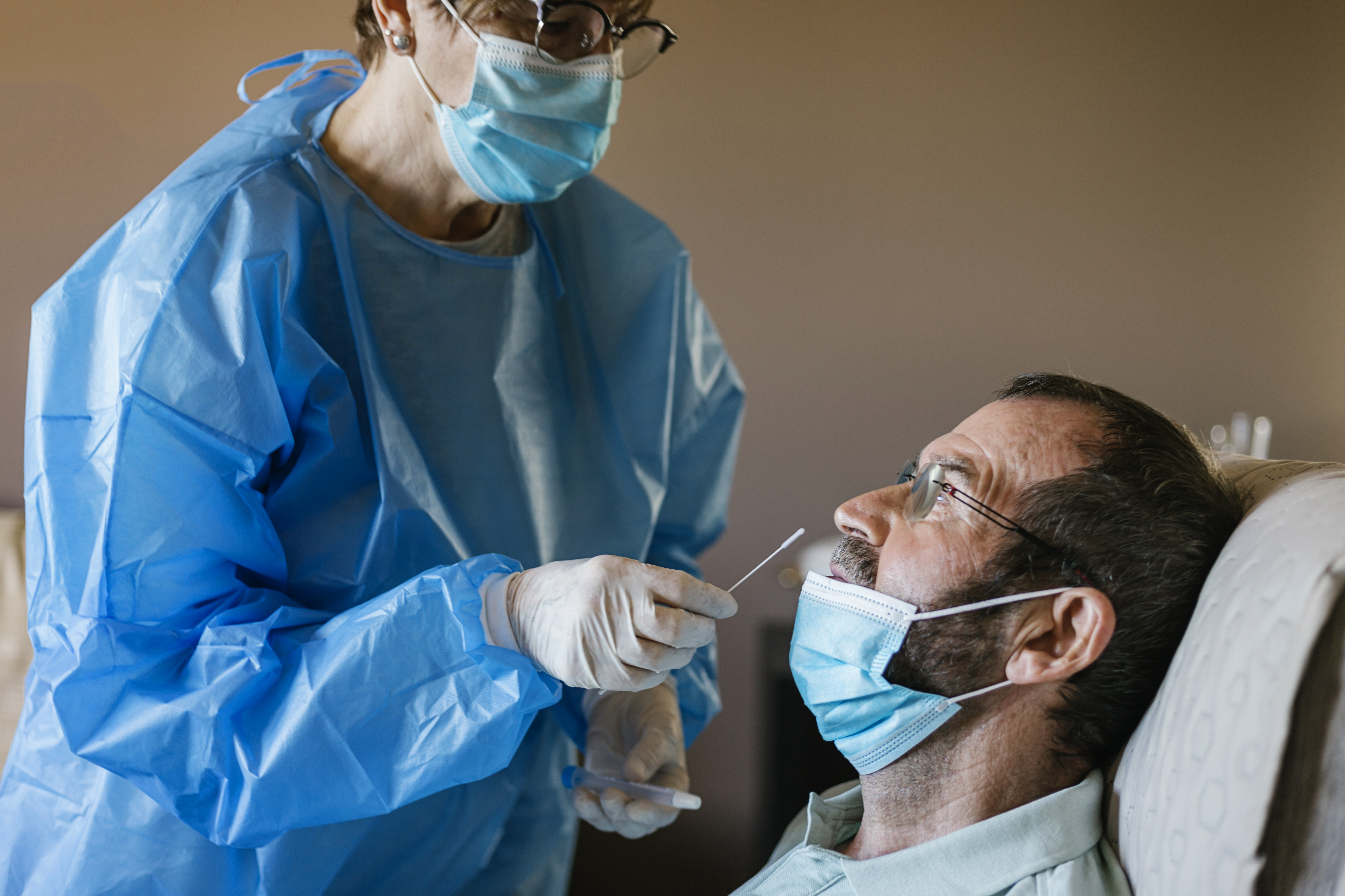 Doctor doing a nasal PCR test on a patient at nursing home