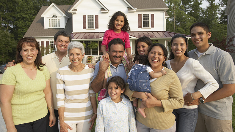 Multi-generational Hispanic family smiling in front of house