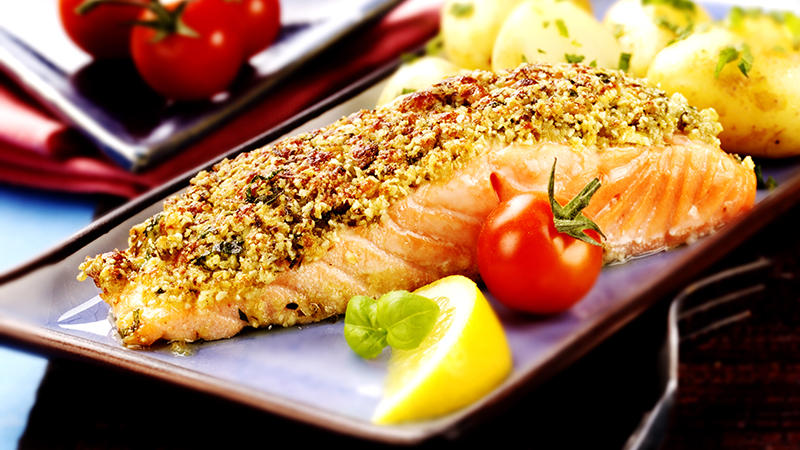 A close-up view of baked salmon with a pesto crust on a plate