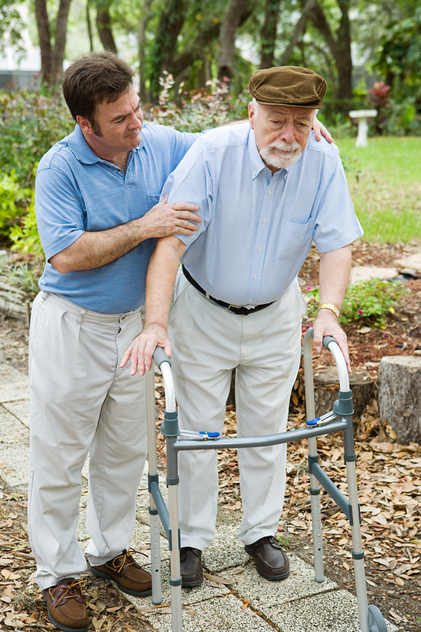 A man helping his elderly father walk