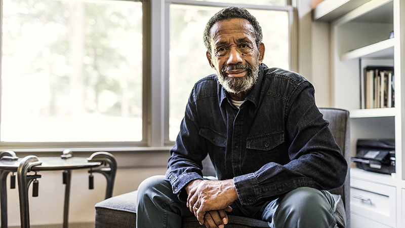 A man sitting on a chair at home and looking straight ahead