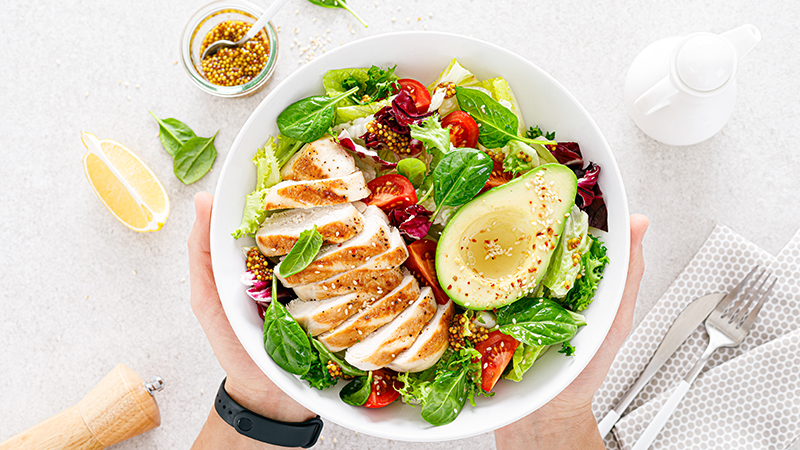 An overhead view of grilled chicken meat and vegetable salad in a bowl