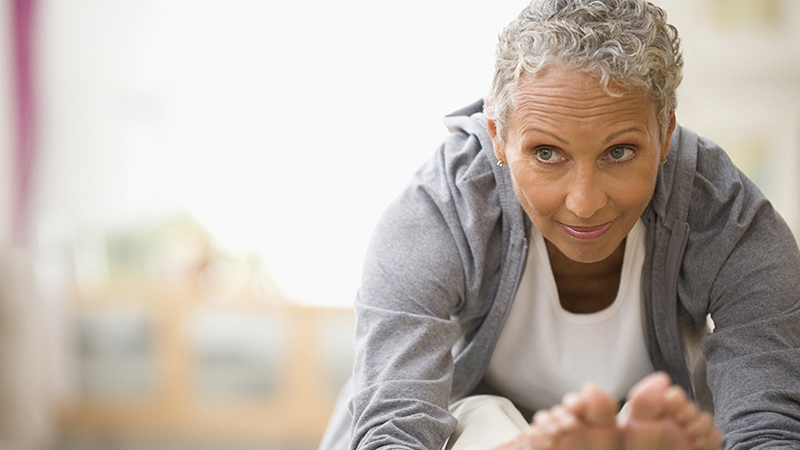 A woman leaning forward to stretch her legs on a yoga mat