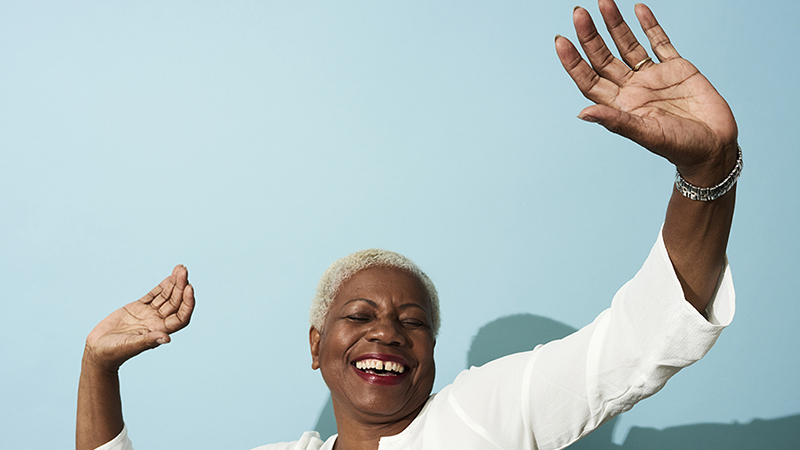 A woman smiling and dancing in front of a blank wall