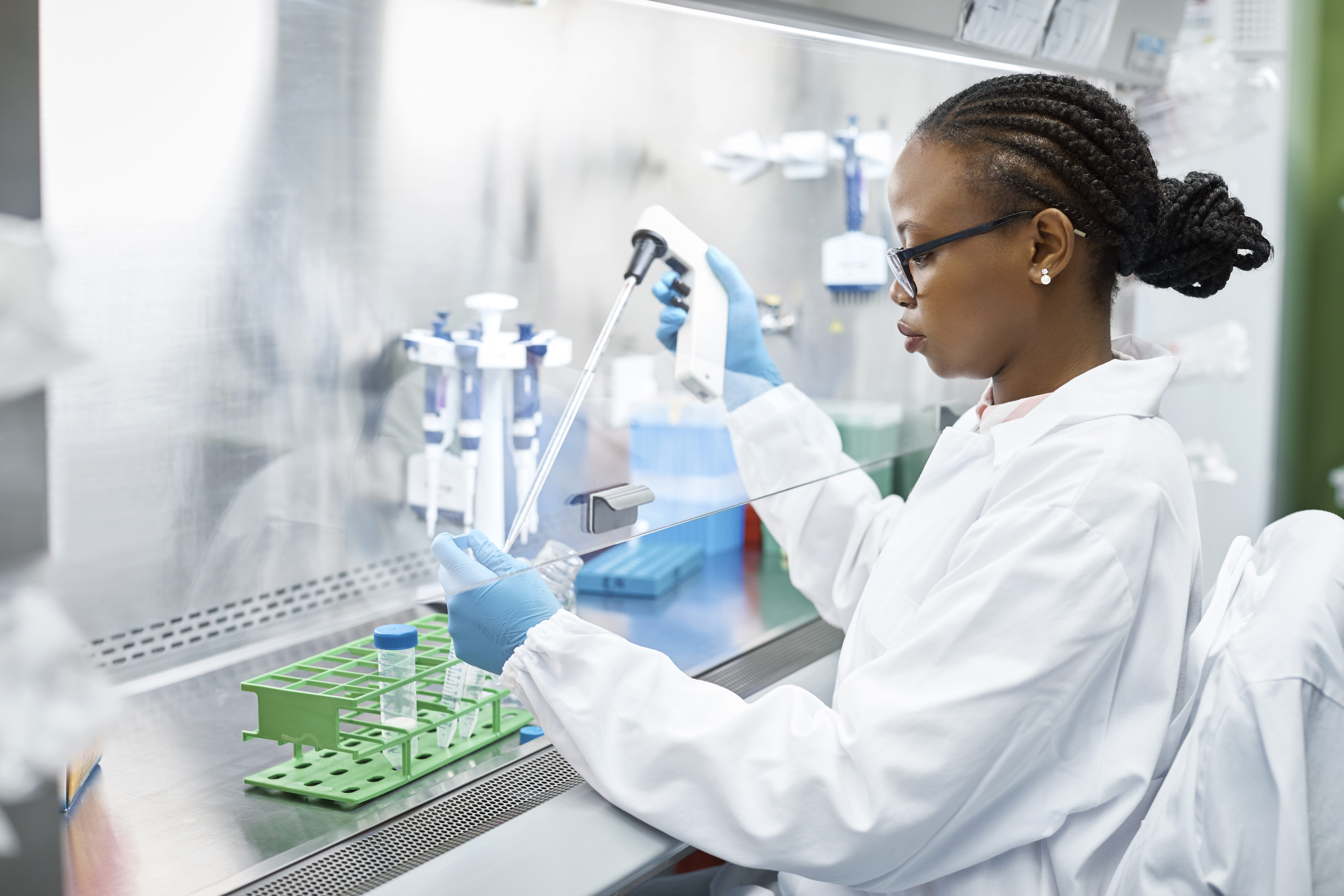 Female scientist analyzing medical sample in test tube. Young researcher is wearing lab coat. She is concentrating while working in laboratory.