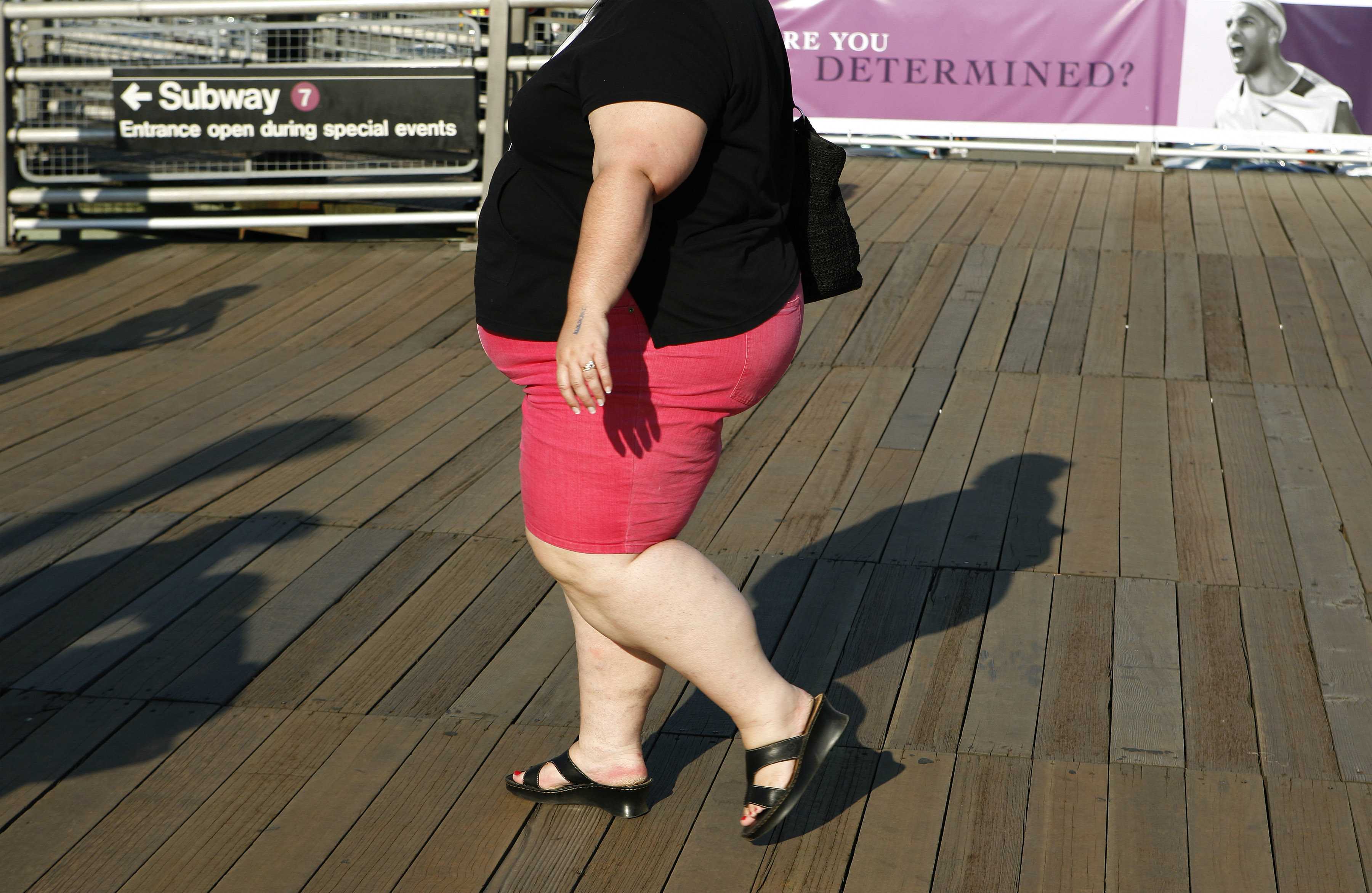 An obese woman walks on the boardwalk