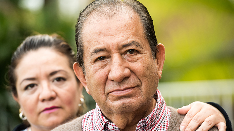 A man and his female caregiver standing behind him