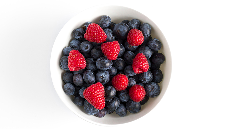 A bowl of blueberries and strawberries against a white background