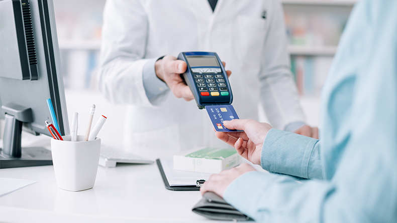 Woman at the pharmacy purchasing medicines and medical products, she is inserting the credit card in the terminal