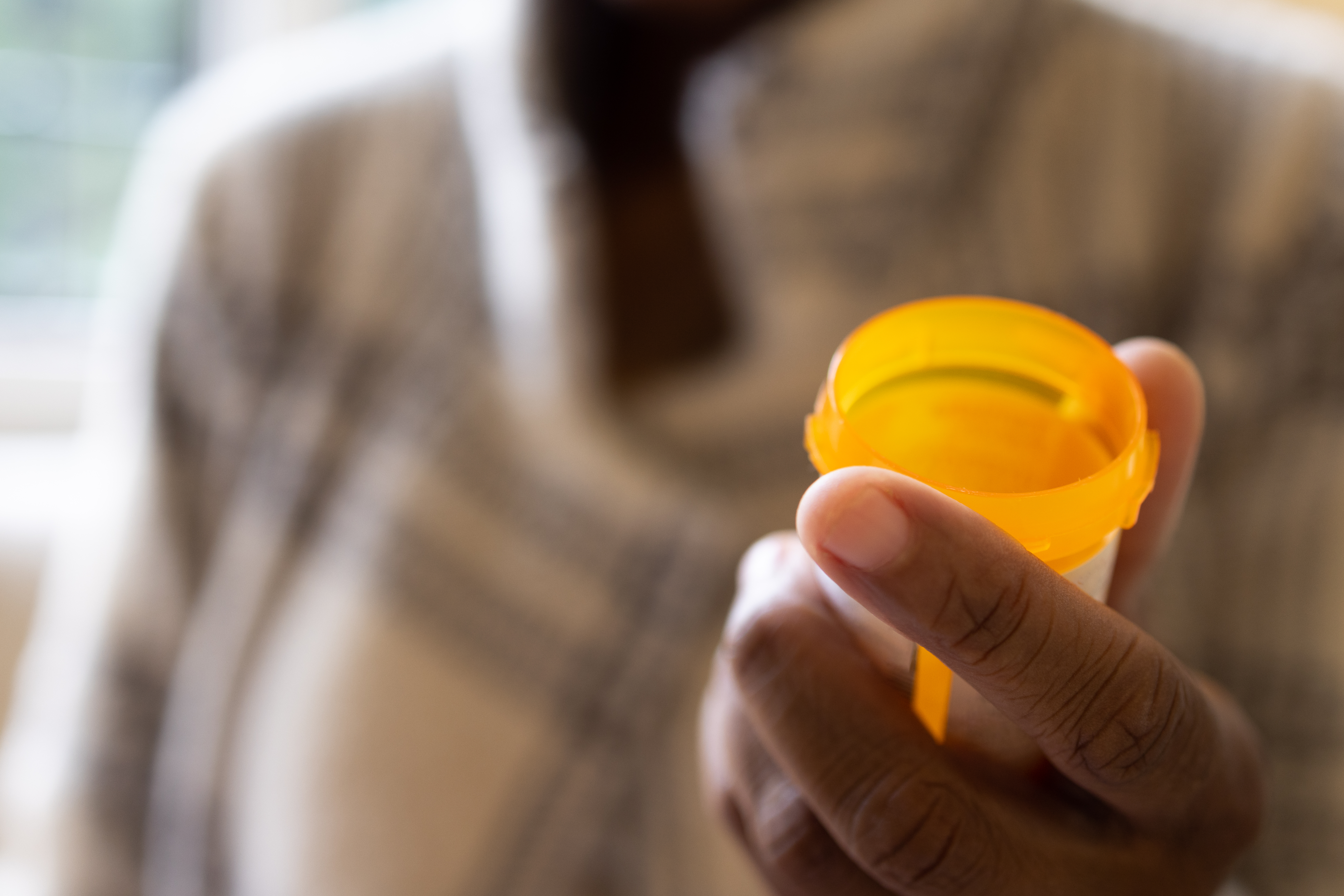 black woman holding open prescription pill bottle