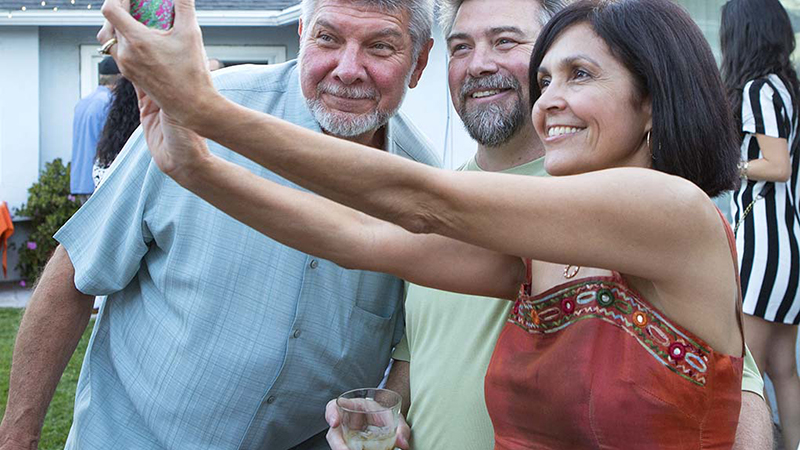 A woman taking a selfie with two men outside