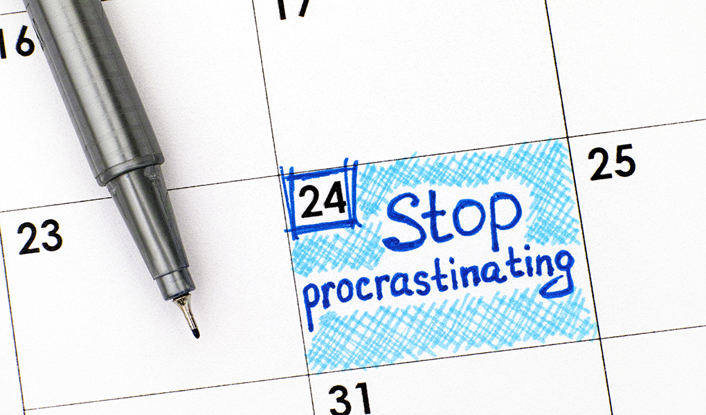 A close-up view of a calendar with "Stop procrastinating" written on it