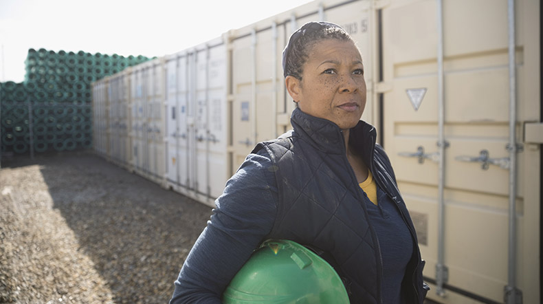 Serious female African American worker in industrial container yard