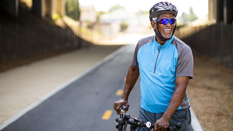 A smiling man on his bicycle on a bike trail