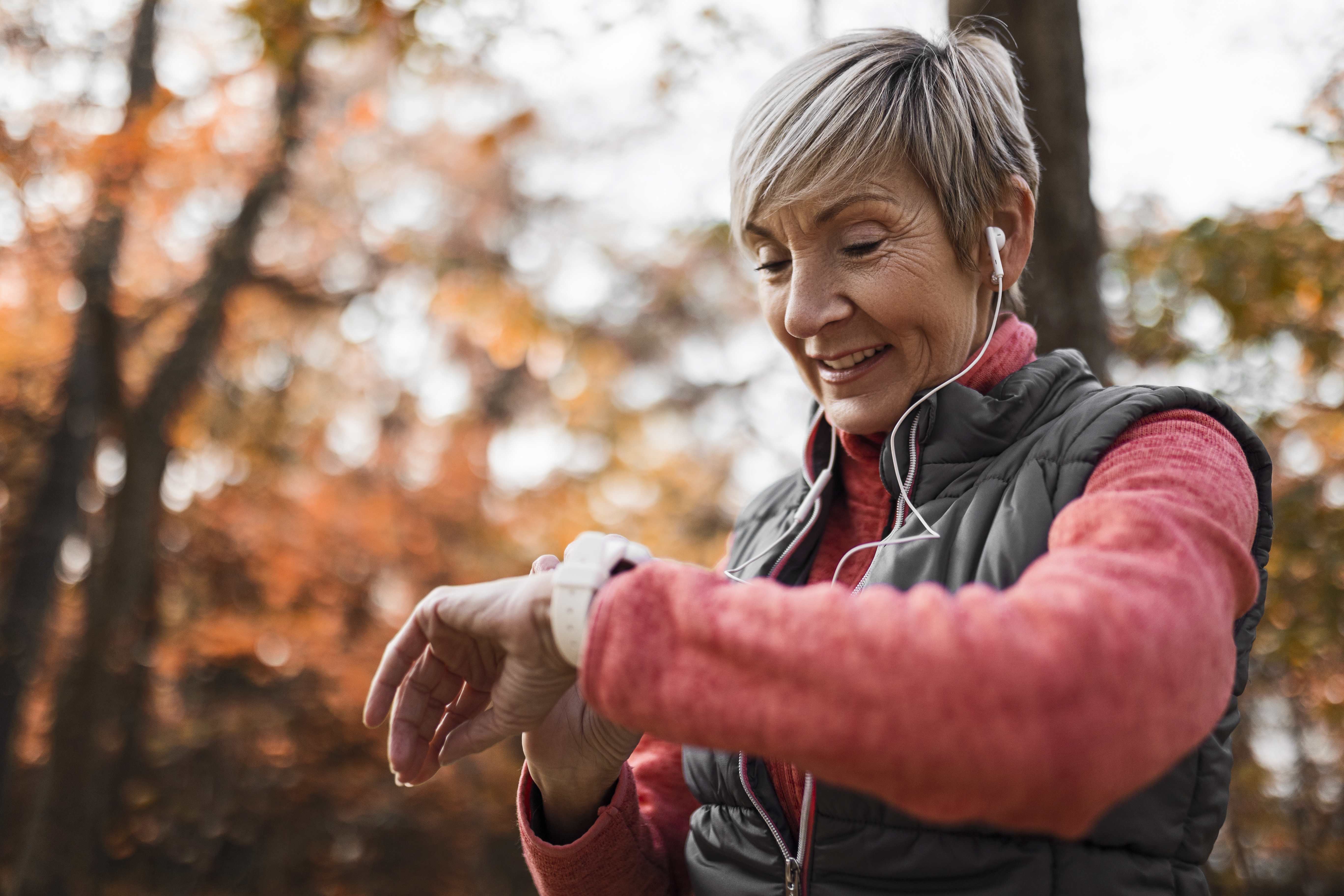 Senior Woman looking at smart watch wearing headphones