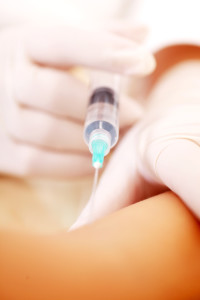 Close-up of doctor's hands holding an injection and giving it to the hand of patient.