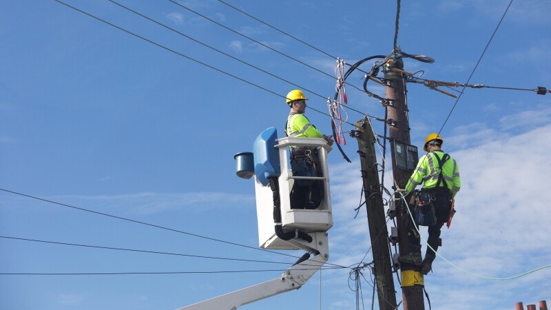 Hombres trabajan con líneas eléctricas en un poste