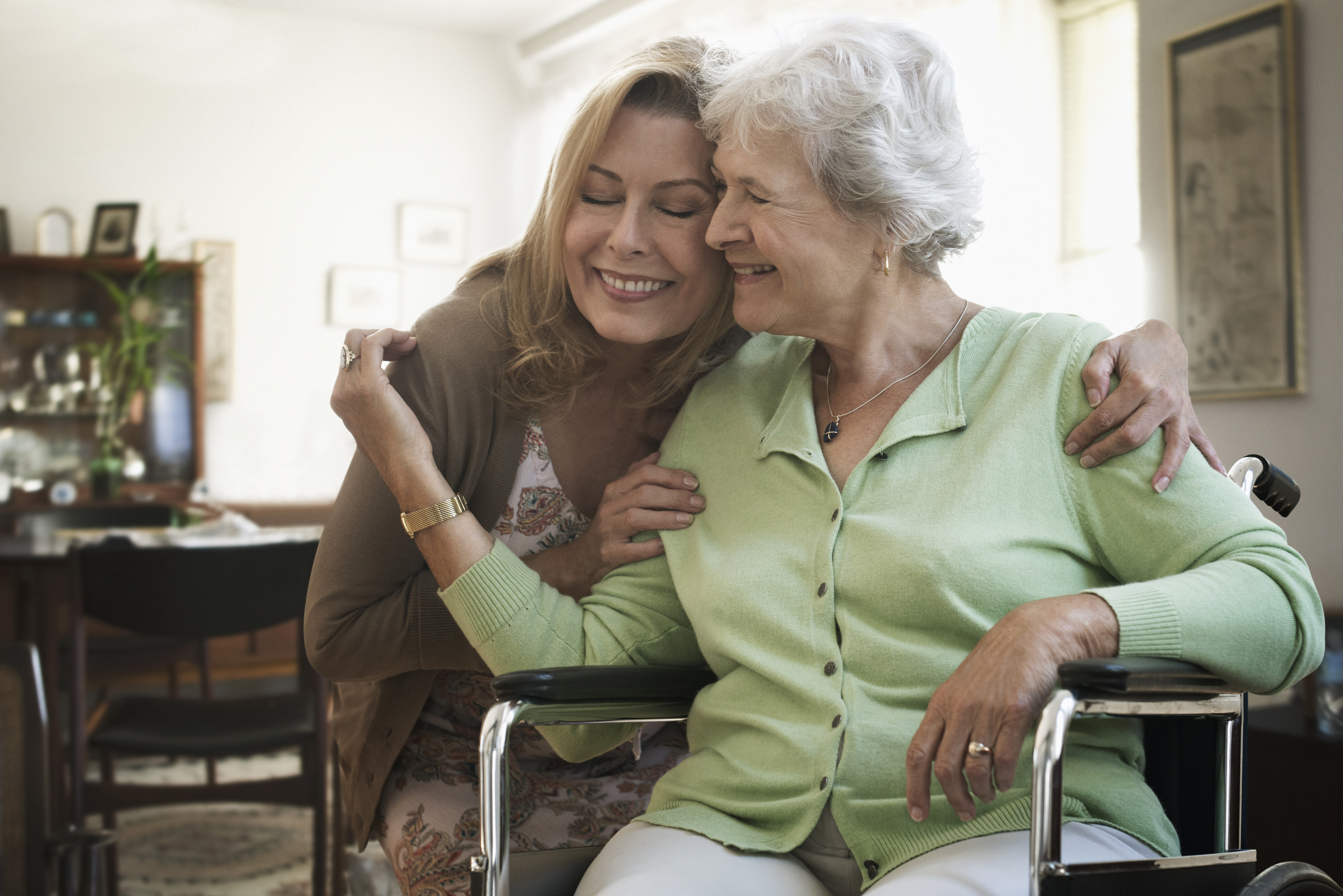 Caregiver hugging mother in wheelchair