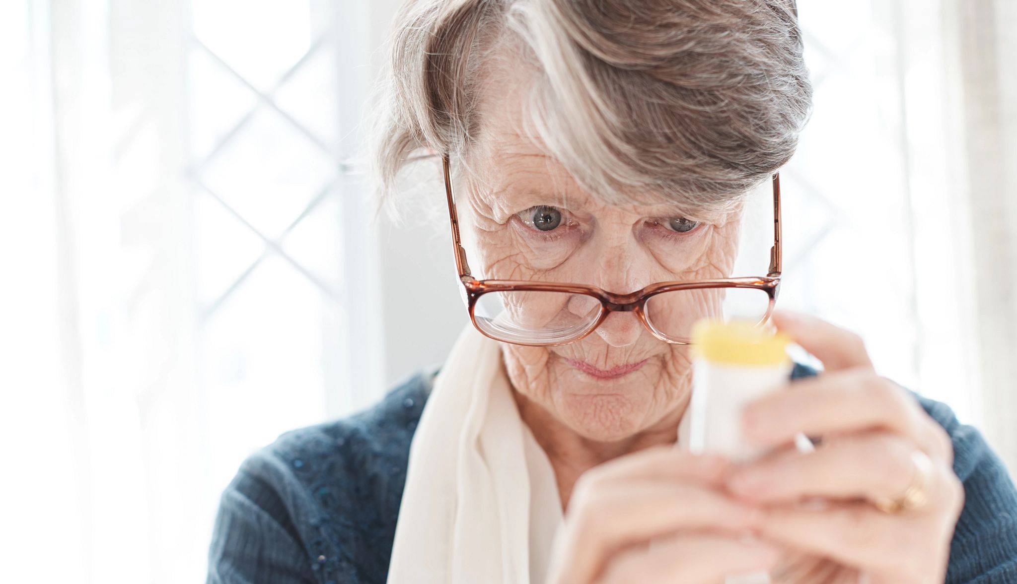 Woman looks at bottle of medication.