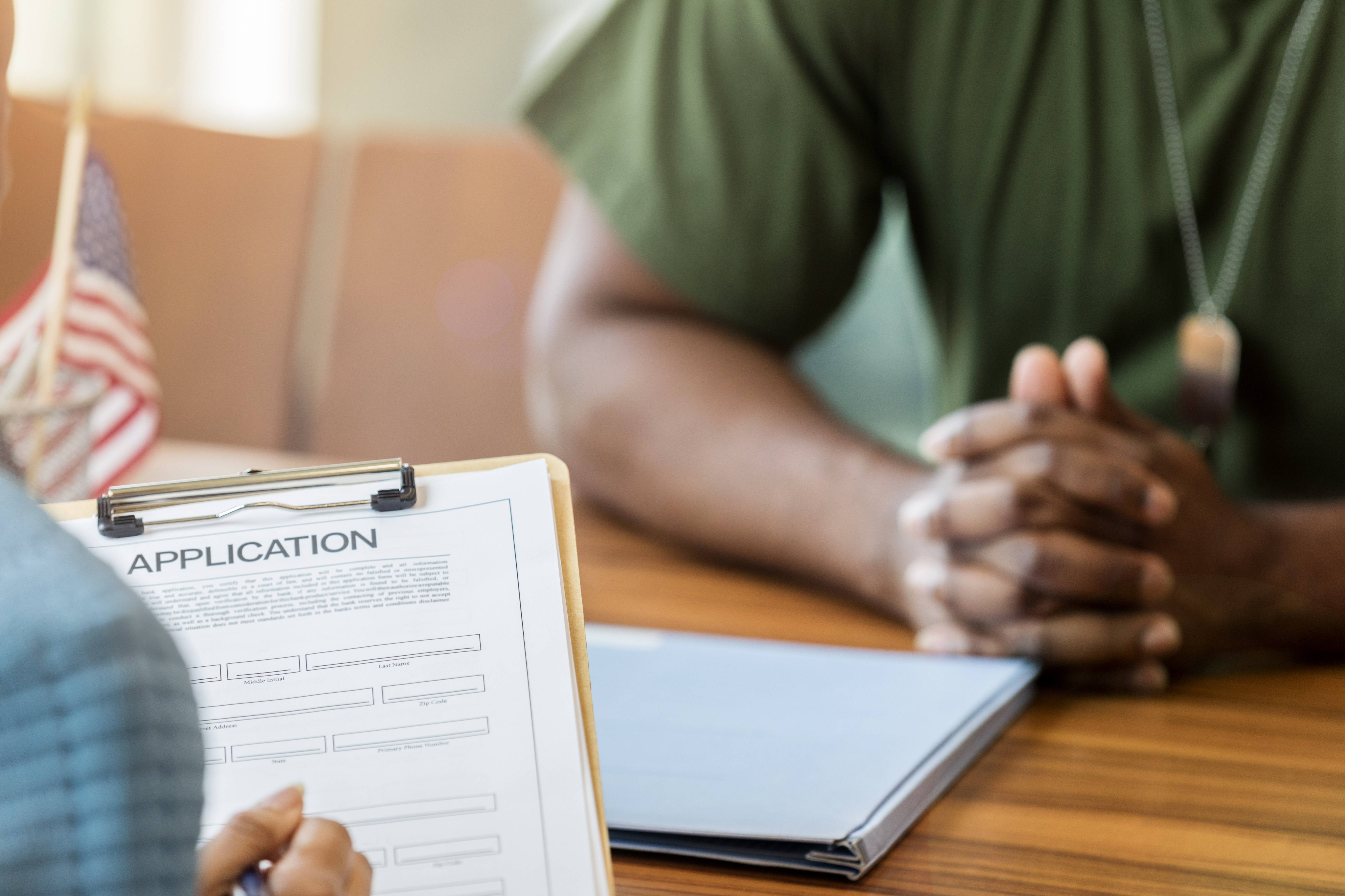 Close up of bank loan application and soldier's clasped hands