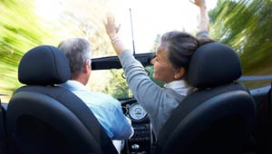 Couple rides in convertible car.