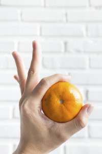 Holding orange on white brick background