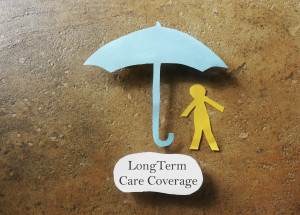 Paper person under an umbrella with Long Term Care Coverage text -- elder care insurance concept