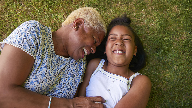 A woman and girl lying in the grass and laughing