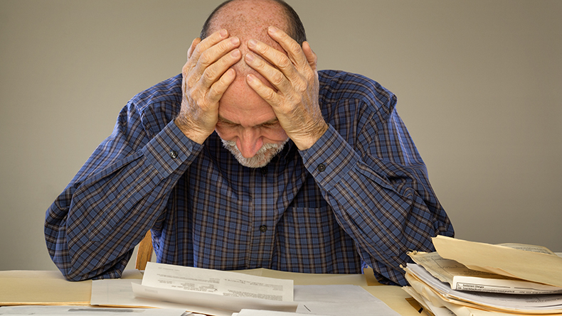 Depressed Senior Adult Man With Stacks of Papers and Envelopes