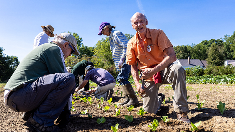 Nick Krembs smiling as he gardens on one knee with others