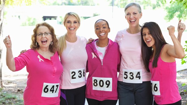 A group of women smiling together after finishing a breast cancer awareness race