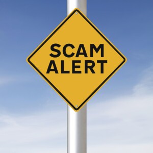 Yield sign with scam alert written on it. Photog: AmanaLang http://www.istockphoto.com/profile/amanalang