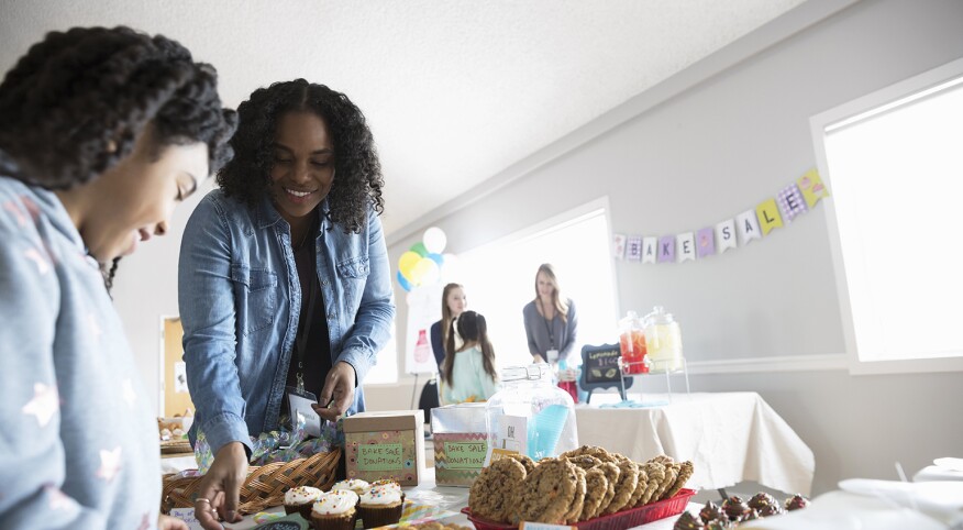 women volunteering at their children's event standing near the dessert table