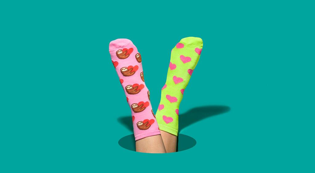 Feet wearing two different socks on a teal background