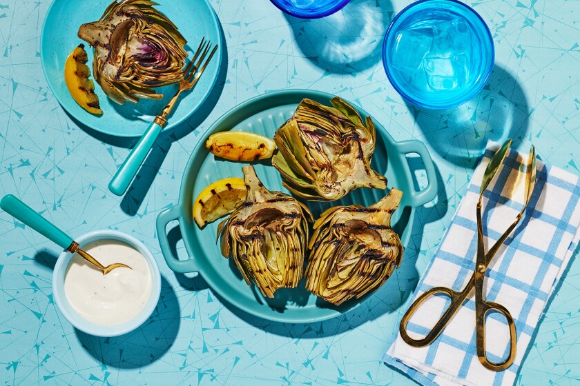 Grilled Artichokes on a bright blue plate with surrounding blue elements