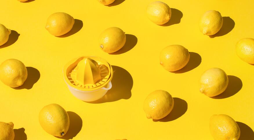 Lemons spread out on yellow paper with a lemon juicer 