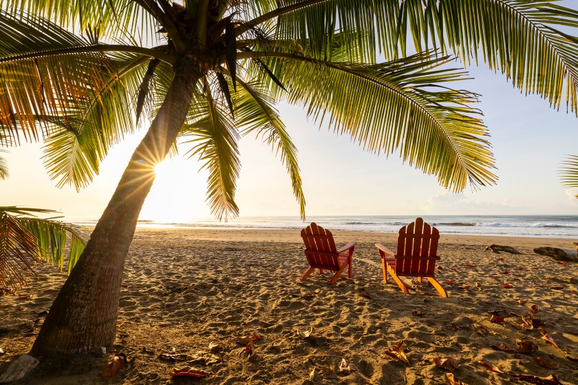 Two chairs under palm trees on Jacó Beach