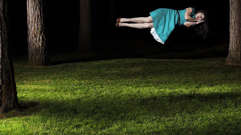 A woman floating in the air as she sleeps outside