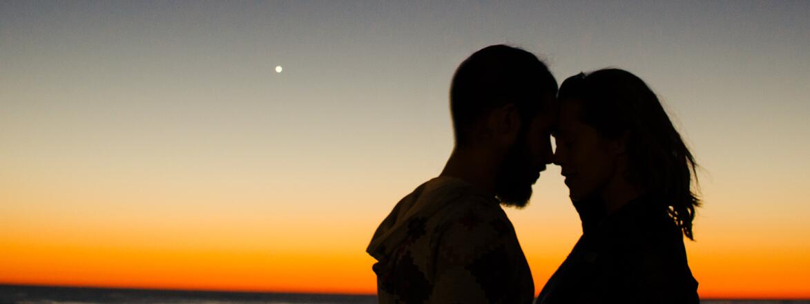 couple embracing in front of sunset