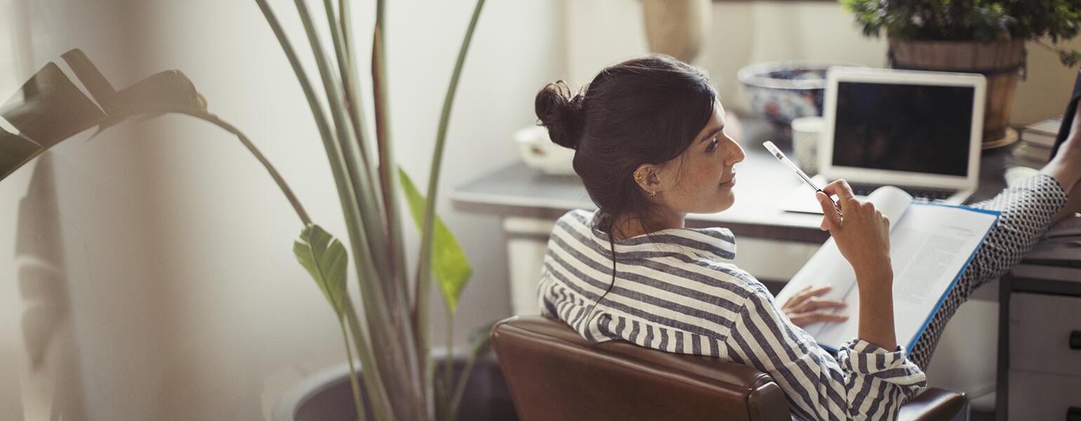 Businesswoman reading paperwork with feet up on desk