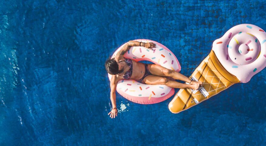 Young Woman Floating In Big Swimming Pool On Inflatable Donut