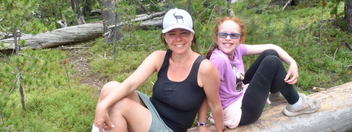 photo of author and her daughter outside hiking sitting on a log