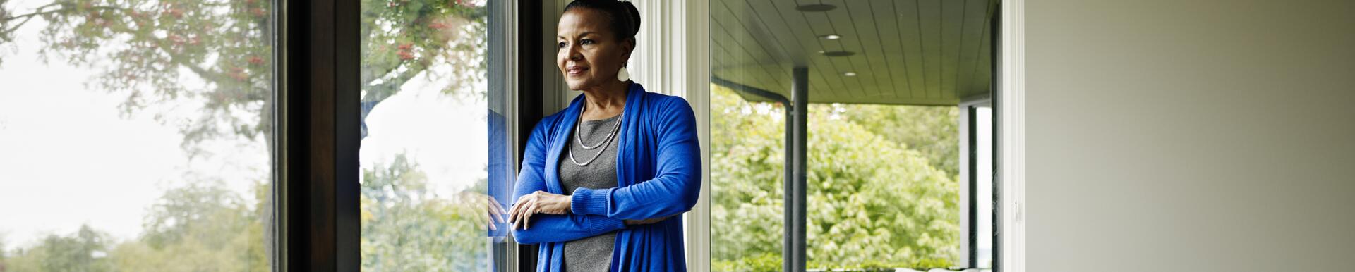 Woman standing arms crossed looking out window