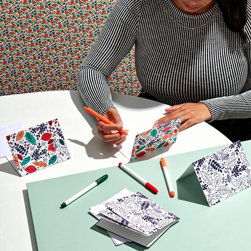 Woman writing inside colorful greeting card with markers