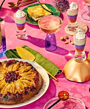 Table of beautiful desserts including cake, bars and pudding on bright pink background