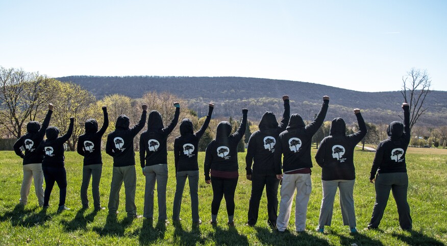 Black women hiking group empowering each other with fists in air outside.