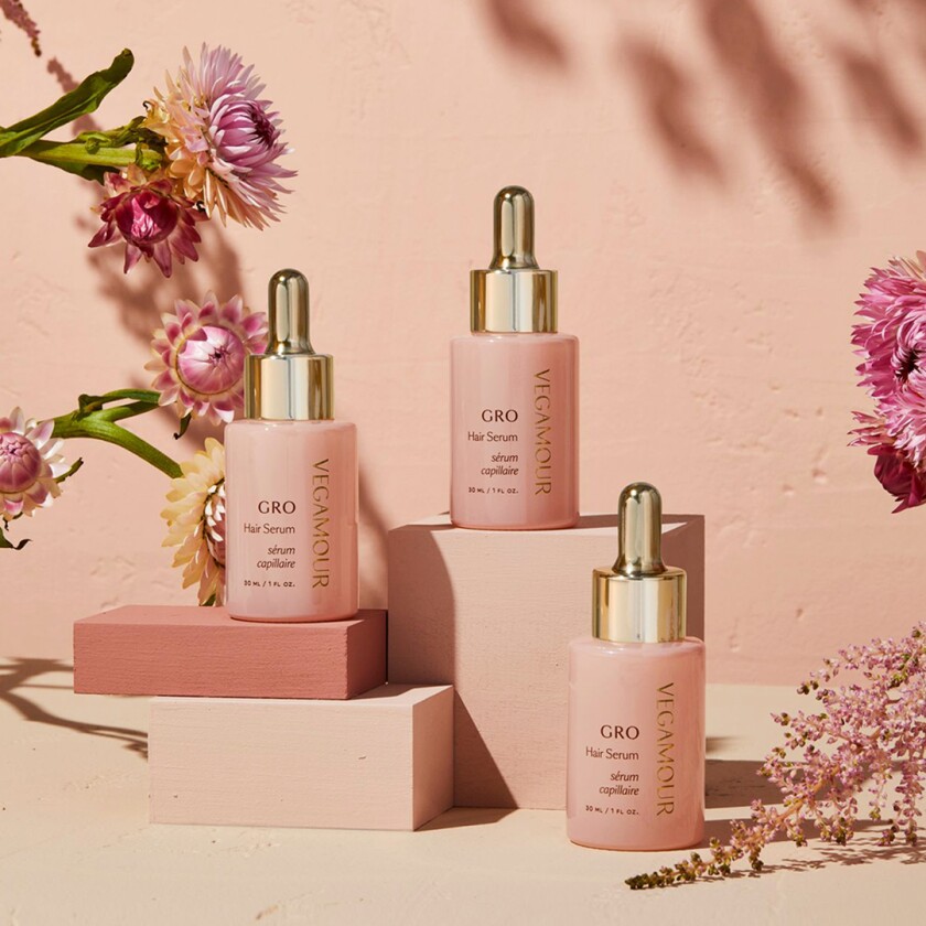 Product shot on pink background with flowers of thin hair activating serum